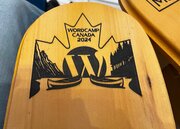 WordCamp Canada logo on arm of Muskoka chair - it shows two canoes on a lake in the mountains, with a backdrop of a maple leaf and the WordPress logo.